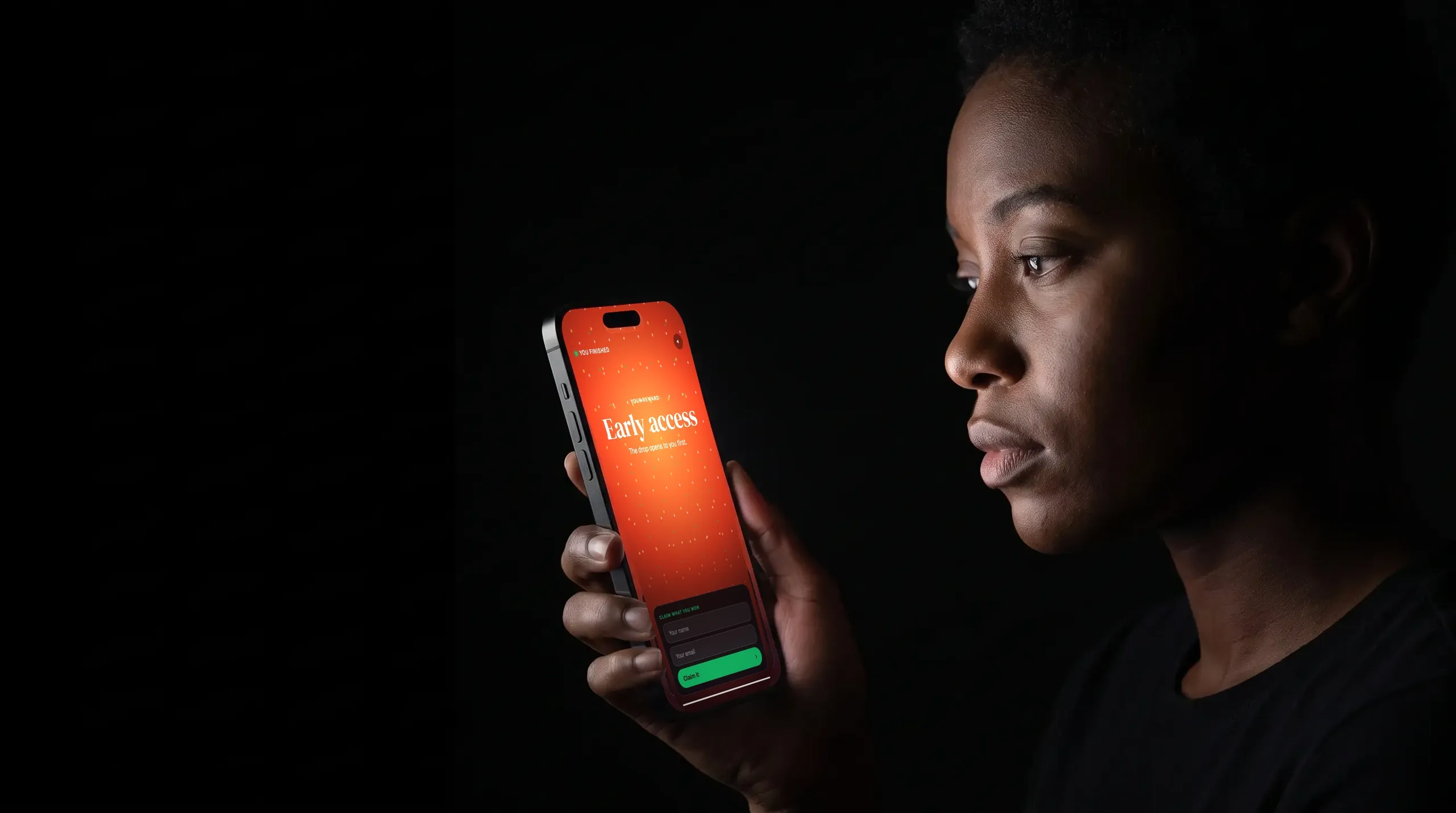 A person in a dark room lit only by their phone, playing for an early access reward