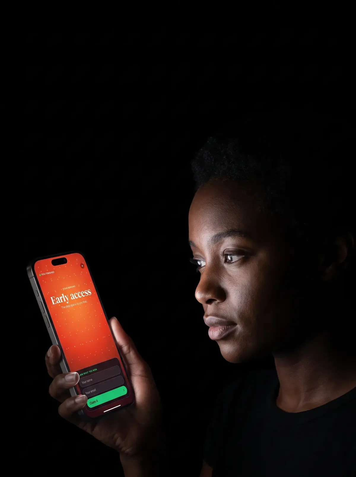 A person in a dark room lit only by their phone, playing for an early access reward