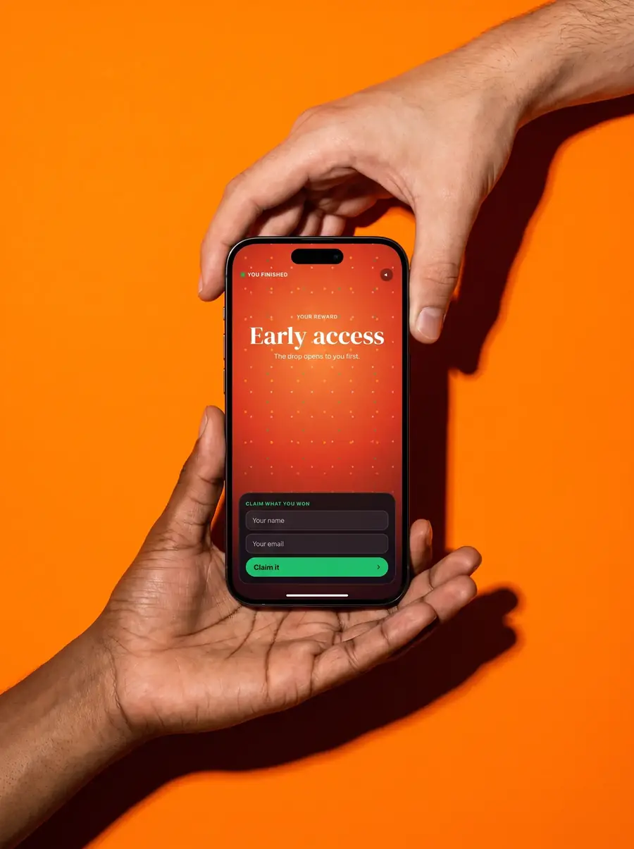 One hand passes a phone to another on an orange backdrop, the screen asking for a name to claim a reward