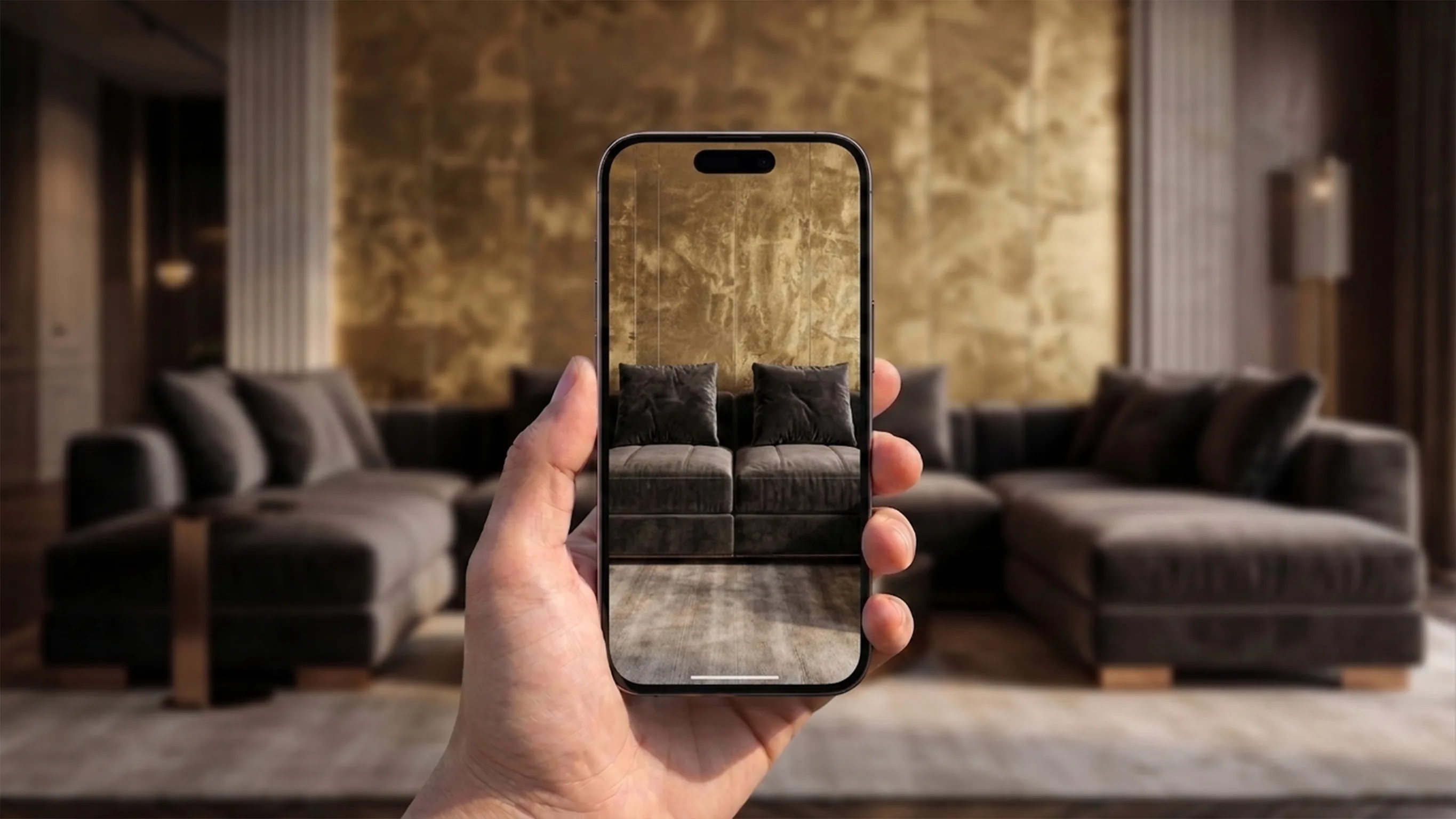 A hand holds a phone playing a sofa video, with a lounge and its gold wall behind it.